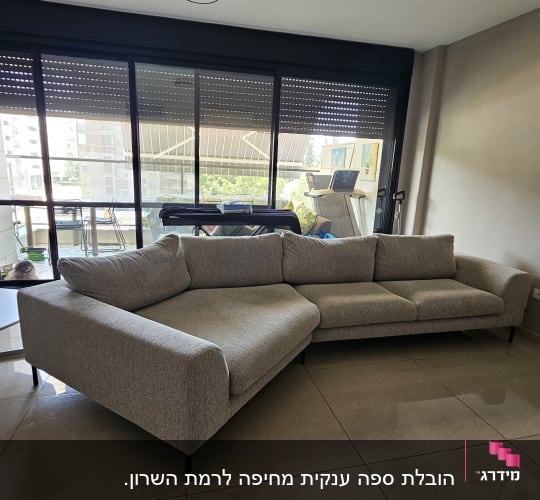 ספה אפורה ליד חלון גדול עם וילון מוגף